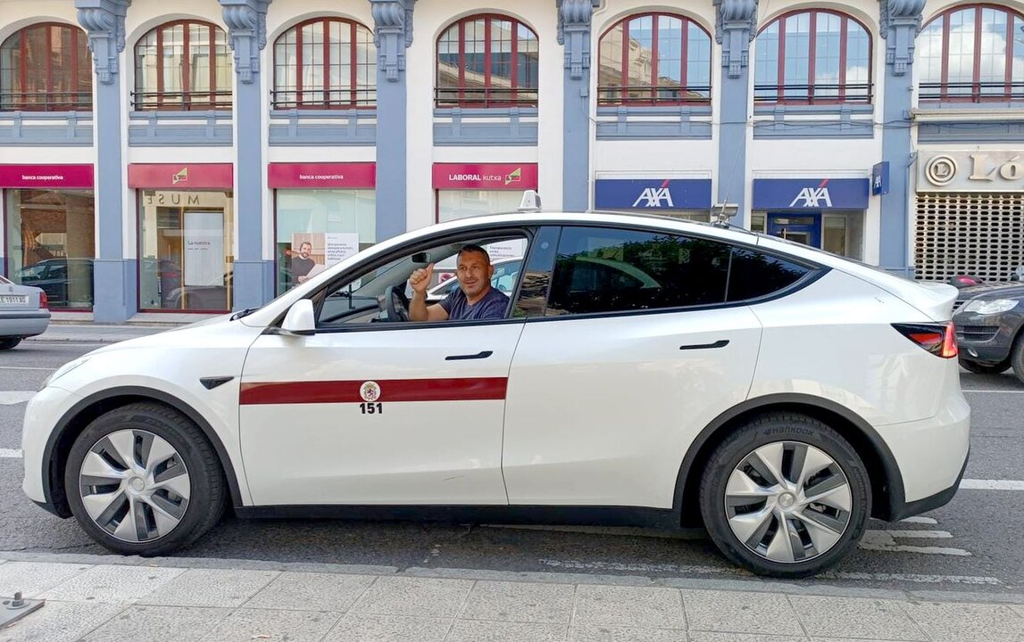 Un taxista con su vehículo eléctrico, en su parada del centro de la ciudad.