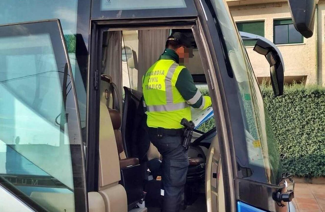 Un guardia civil realiza el control de un vehículo de transporte escolar.