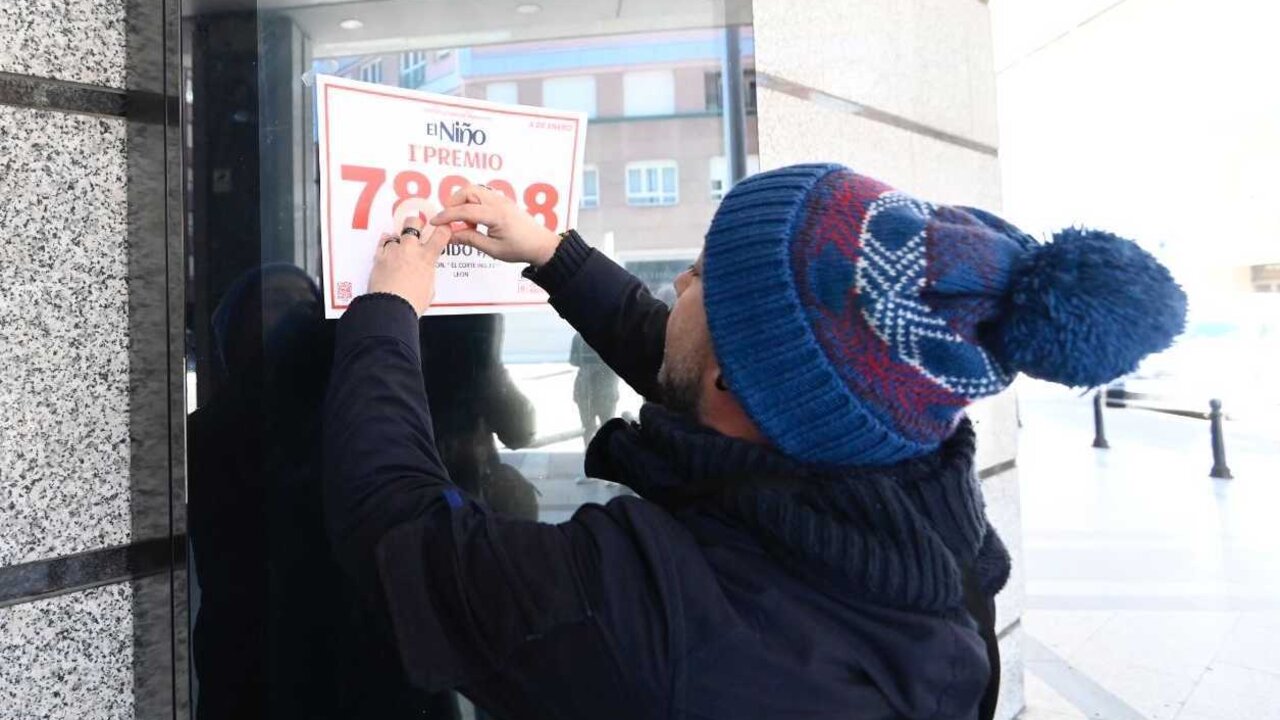 Un afortunado pega el cartel con el número agraciado en la fachada de El Corte Inglés. Foto: Campillo