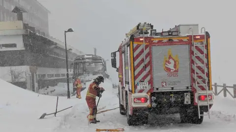 El incendio durante la madrugada de un autobús en un estacionamiento próximo a la estación invernal de San Isidro ha tenido que ser sofocado este jueves con el uso de una 'fresadora' quitanieves hasta la llegada de Bomberos Diputación, complicada por la tormenta 'Ivo' sobre la zona. Fotos: Sepeis